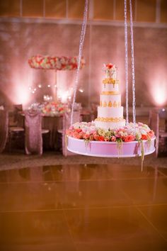 a wedding cake sitting on top of a white table covered in pink and red flowers