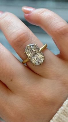 a close up of a person's hand with a ring on their finger and an oval shaped diamond in the middle