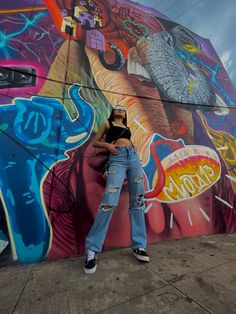 a woman standing in front of a colorful wall with graffiti on it's sides