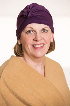 a woman wearing a purple head wrap and smiling