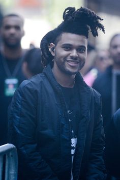 a young man with dreadlocks standing in front of a group of other people