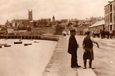 an old black and white photo of two people standing on the side of a road