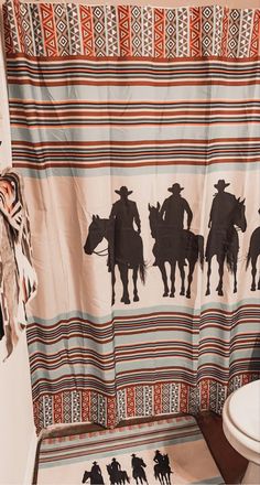 a shower curtain with cowboy silhouettes on it in a bathroom next to a toilet