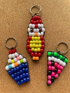 three keychains made out of legos on a cork board surface with one being colored and the other is shaped like an ice cream cone