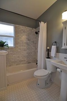 a white toilet sitting next to a bath tub under a bathroom window in a bathroom