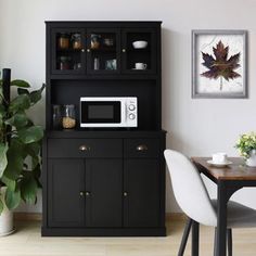 a kitchen area with a microwave, potted plant and dining room table