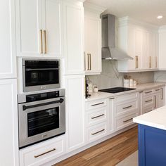 a kitchen with two ovens and white cabinets on the counter top, along with a blue island