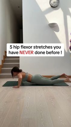 a woman is doing yoga on the floor in front of stairs with a clock above her