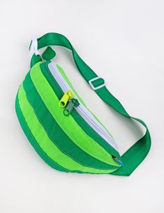 Squeeze the day with this rad fanny pack that also doubles as a cross-body bag! Features a double pull main zipper compartment and lining pocket. Constructed with with water resistant 100% nylon pack cloth. Color block rind & embroidered design detail. Explore all Fruit Slice Slings Adjustable 1.5" nylon seat belt webbing strap. Total Bag + strap circumference minimum- 35"Total Bag + strap circumference maximum- 51" 12.5" wide x 5.5" high x 6" deep, .5 lbs CapacityMain Compartment- 3.5 L Made in Green Functional Belt Bag With Adjustable Strap, Green Outdoor Crossbody Belt Bag, Functional Green Belt Bag With Adjustable Strap, Green Belt Bag With Cell Phone Pocket For Outdoor, Outdoor Green Belt Bag With Removable Pouch, Functional Green Crossbody Belt Bag, Green Crossbody Belt Bag With Removable Pouch, Functional Green Shoulder Bag With Zipper, Functional Green Shoulder Bag With Zipper Closure