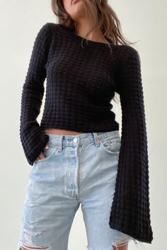 a woman wearing ripped jeans and a black sweater