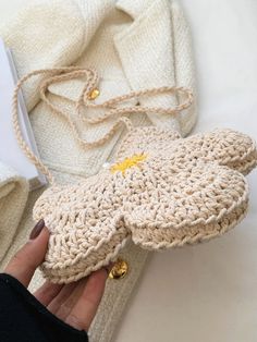 a hand is holding a crocheted mitt next to other knitted items