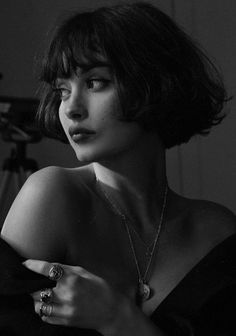 a black and white photo of a woman with short hair, wearing a ring and necklace