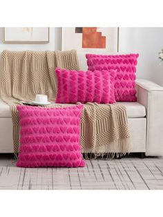 four pink pillows sitting on top of a white couch