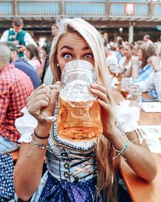 a woman is holding up a beer in front of her face