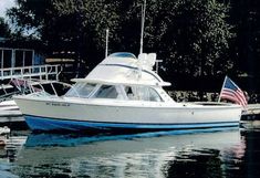 a white boat with an american flag on it is in the water next to a dock