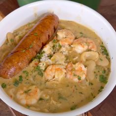 a white bowl filled with soup and a sausage