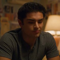 a young man sitting in front of a lamp