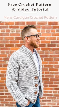 a man standing in front of a brick wall wearing a gray cardigan and jeans