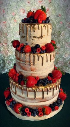 a three tiered cake with berries and chocolate drizzled on top