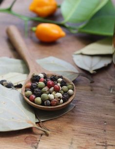 a wooden spoon filled with nuts on top of a table next to oranges and leaves