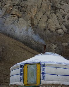 a yurt sitting in front of a rocky mountain