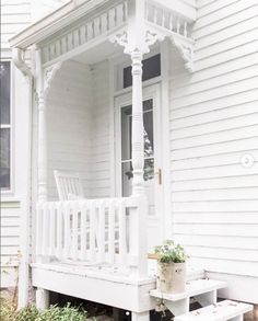 a white porch with a bench and potted plant on the front step next to it