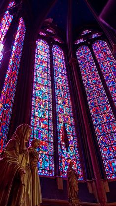 a statue in front of two large stained glass windows