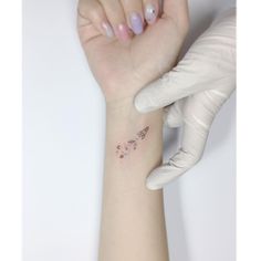 a woman's hand with a small tattoo on her left wrist and an arm glove