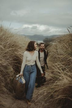 a man and woman walking through tall grass