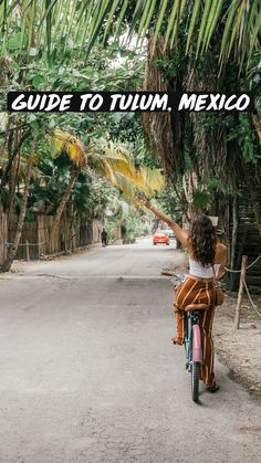 a woman riding a bike down a street with palm trees in the background and text reading guide to tulum, mexico