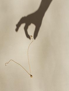 the shadow of a person's hand holding a string with two small beads attached to it