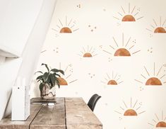 a wooden table sitting in front of a white wall with sun designs on the walls