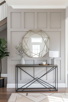 a console table with a mirror and potted plant on it in front of a staircase