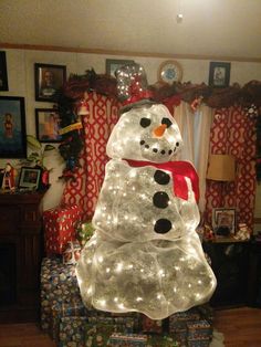 a lighted snowman sitting on top of a pile of presents