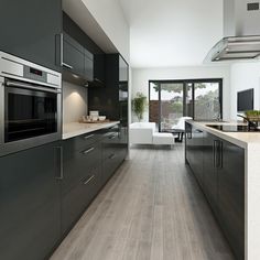 a modern kitchen with wood floors and stainless steel appliances, along with an open floor plan