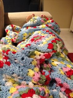 a baby is laying under a crocheted blanket