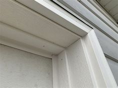 an open window on the side of a house with white siding and wood slats