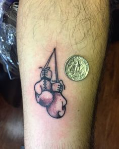 a tattoo on the leg of a man with two boxing gloves hanging from a hook