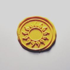 a yellow wax stamp with the sun on it