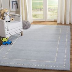 a child's room with a white chair and blue rug