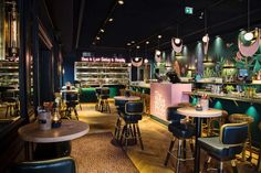 the interior of a restaurant with many tables and stools, lights hanging from the ceiling