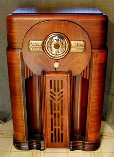 an old fashioned wooden radio sitting on top of a tiled floor next to a wall