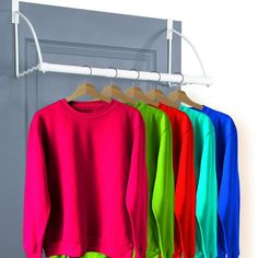 colorful sweatshirts hanging on clothes rack in front of white wall