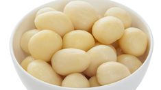 a white bowl filled with peeled and uncooked food items on a white background