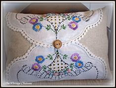 a white pillow with flowers on it and a wooden button in the middle, sitting on a chair