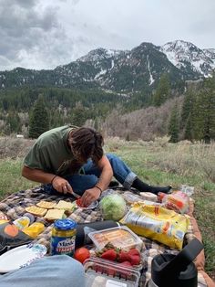 a man sitting on top of a blanket next to food