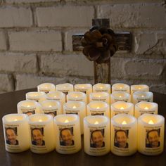 many lit candles sit in front of a cross on a table with an image of a man