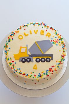 a birthday cake with an image of a dump truck on the top and sprinkles around it