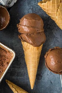 three scoops of chocolate ice cream on top of each other with spoons next to them