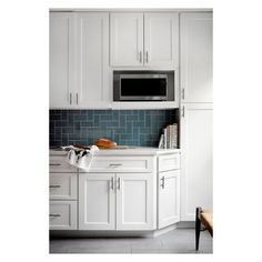 a kitchen with white cabinets and blue tile backsplash, including a microwave oven